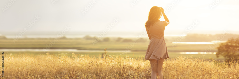 dreamy girl in a field at sunset, a young woman in a haze from the sun enjoying nature, romantic style