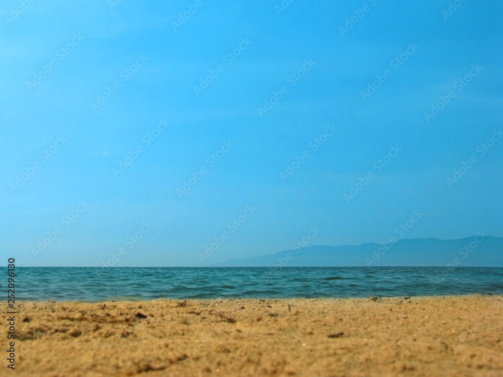 Empty sea beach background. Low horizon with sky and yellow sand. Silhouette of the mountains.