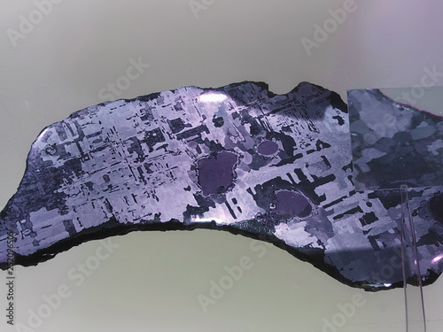 Iron alien meteorite with Widmanstatten pattern on light