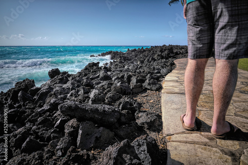 Man Walking on Path by Ocean and Black Lava Rocks