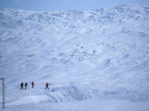 People hike across snowy landscape in Greenland photo