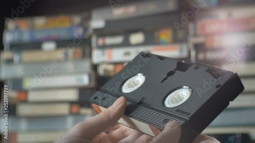 male hand picks up a VHS cassette from the shelf.