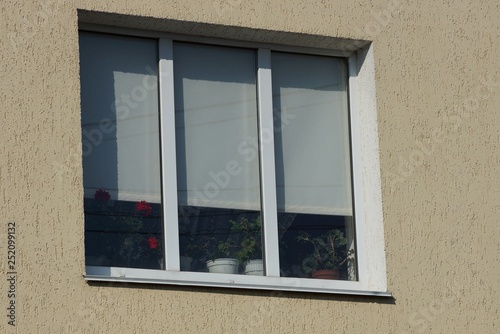 large window with white shutters on the gray wall of the building photo