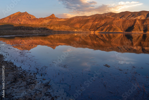 Beautiful sunset landscape. Bright sunlight on a mountain lake, the mountains reflected in the water. Armenia.