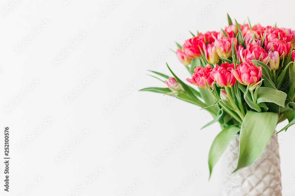 A bouquet of pink red white peony tulips in a gray modern vase on wooden tabel