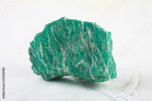 Natural rock amazonite mineral stone from Kola Peninsula on white cement background. photo