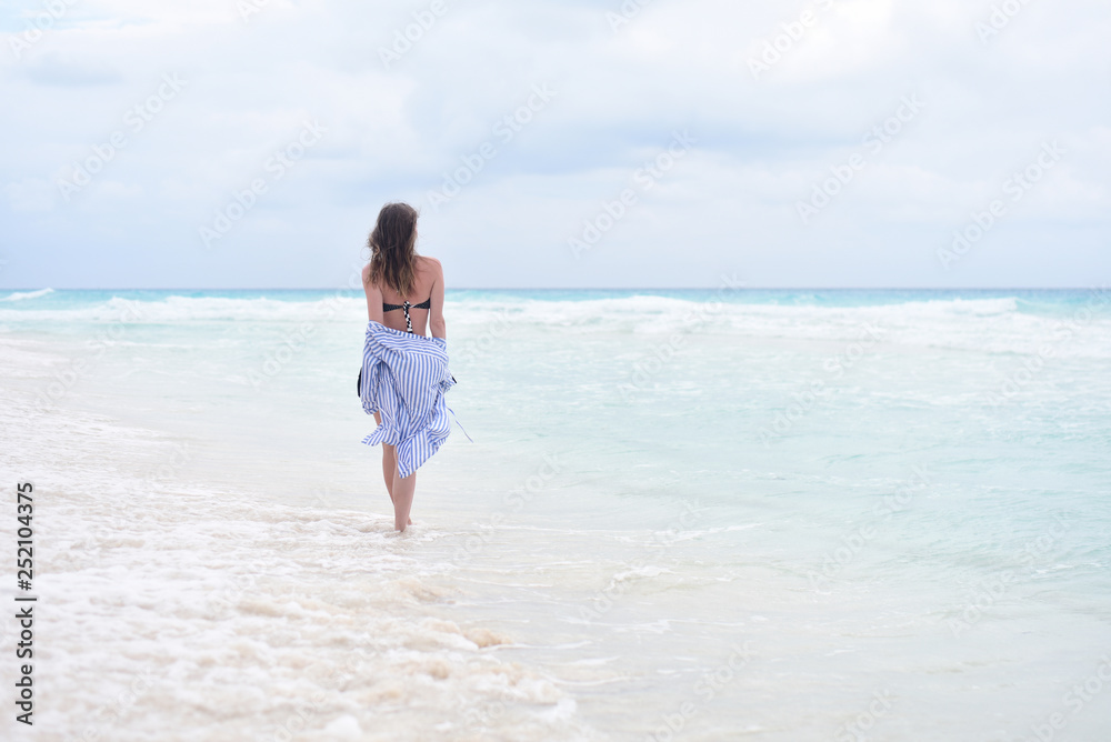 Back view - woman walking along seashore