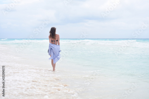 Back view - woman walking along seashore © Alice Nerr
