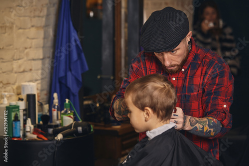 Caucasian boy getting haircut in barbershop indoor