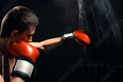 Boy hitting the punching bag on dark background © skif