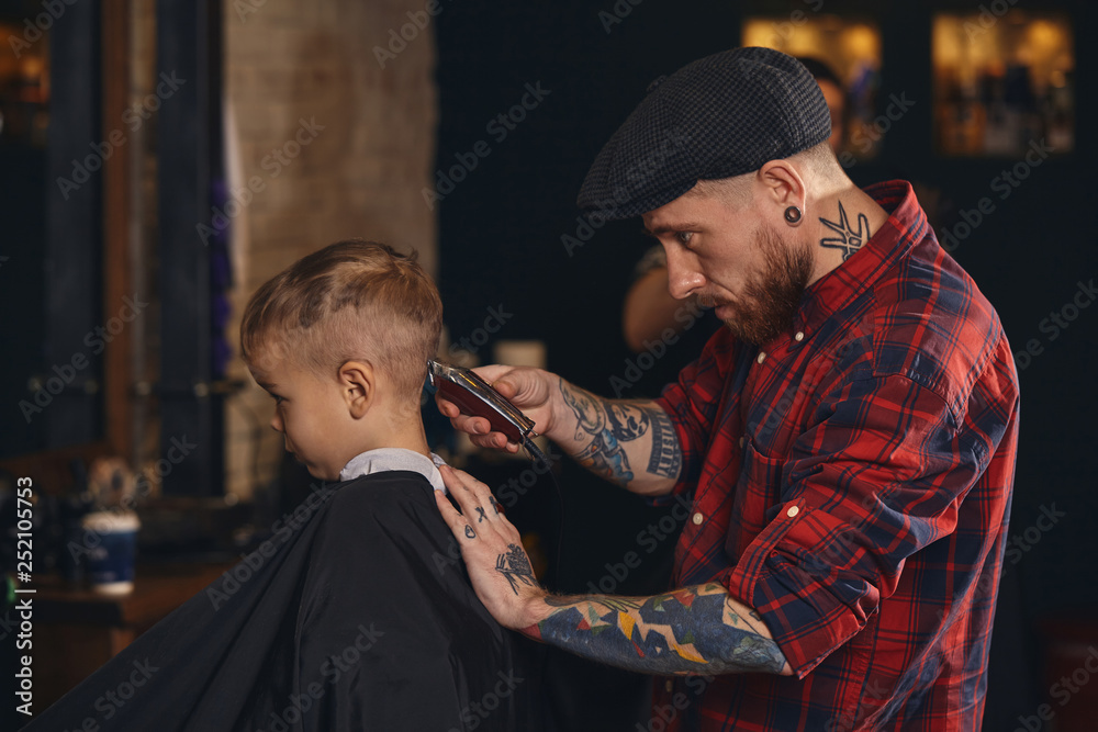 Caucasian boy getting haircut in barbershop indoor