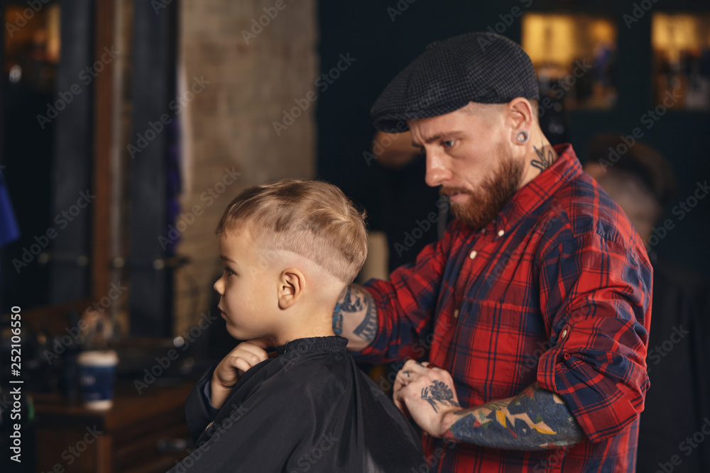 Caucasian boy getting haircut in barbershop indoor