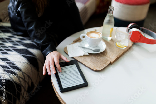 Close-up of young woman in a cafe using e-book