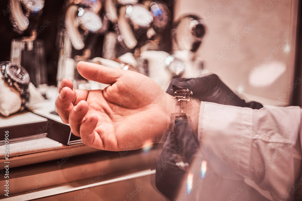 Obraz premium Assistant helps the client to try on exclusive men's watches, close-up hands.
