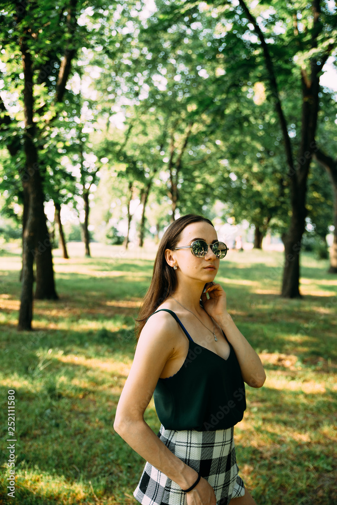 Beautiful young girl in a park in sunglasses Beautiful young girl in a park in sunglasses