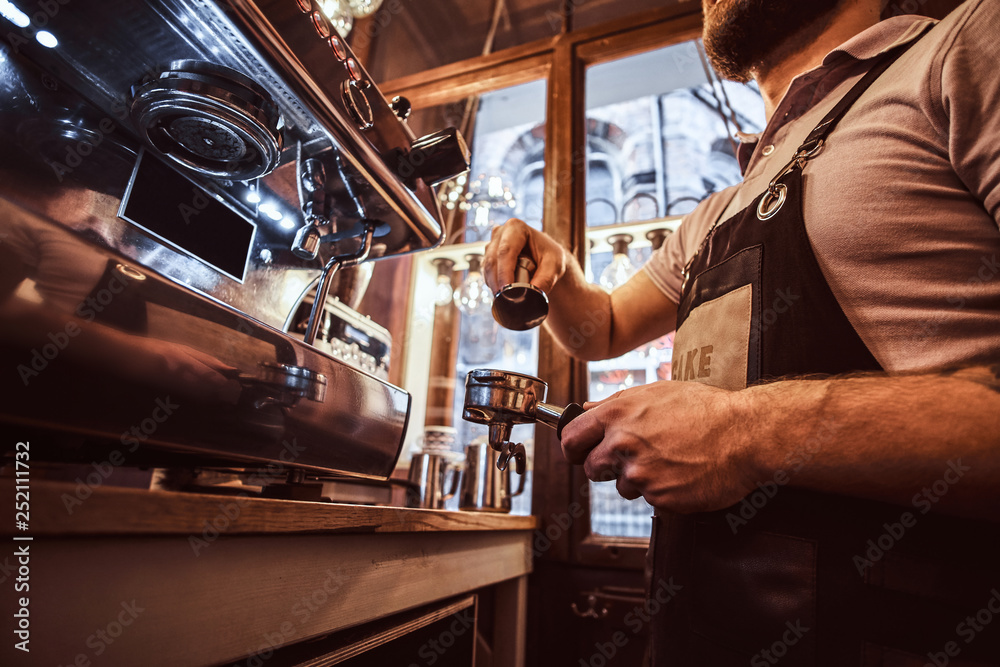 Low angle photo of a barista holding a portafilter, working in the coffee shop or restaurant Low angle photo of a barista holding a portafilter, working in the coffee shop or restaurant