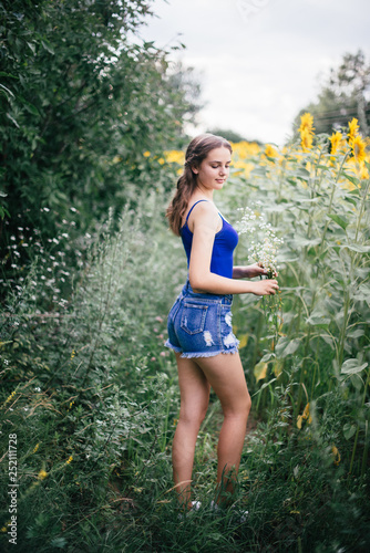 A girl in short shorts and a blue T-shirt with a bouquet of wild flowers