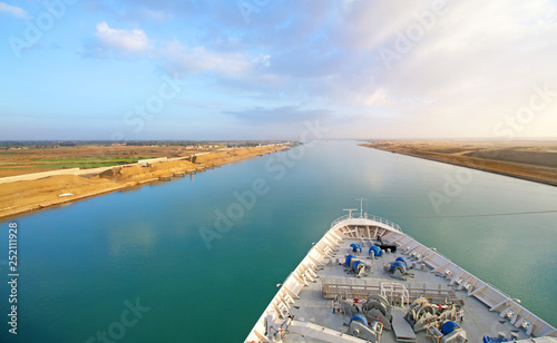 Ship Transiting through Suez Canal. Desert sand on both sides. Ship's bow and rail in the foreground. photo