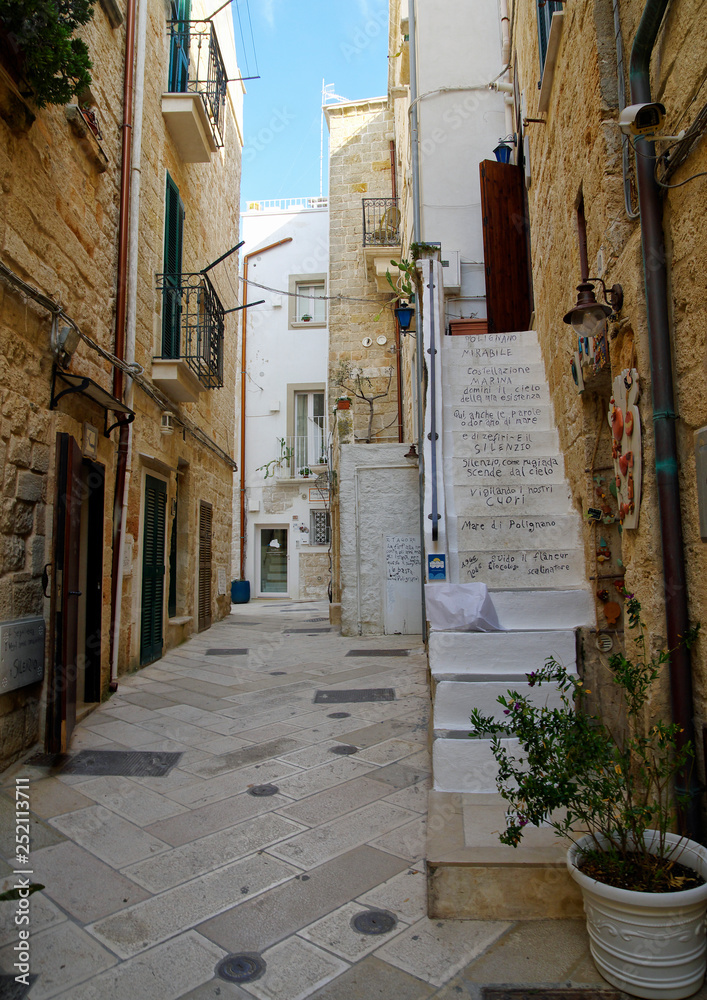 POLIGNANO A MARE, ITALY - MARCH 29th, 2018: Typical narrow street with decorated stairs leading to apartment in center of Polignano a Mare town, Puglia region, Italy.
