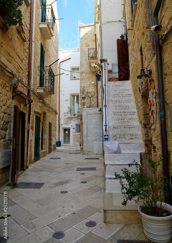POLIGNANO A MARE, ITALY - MARCH 29th, 2018: Typical narrow street with decorated stairs leading to apartment in center of Polignano a Mare town, Puglia region, Italy.