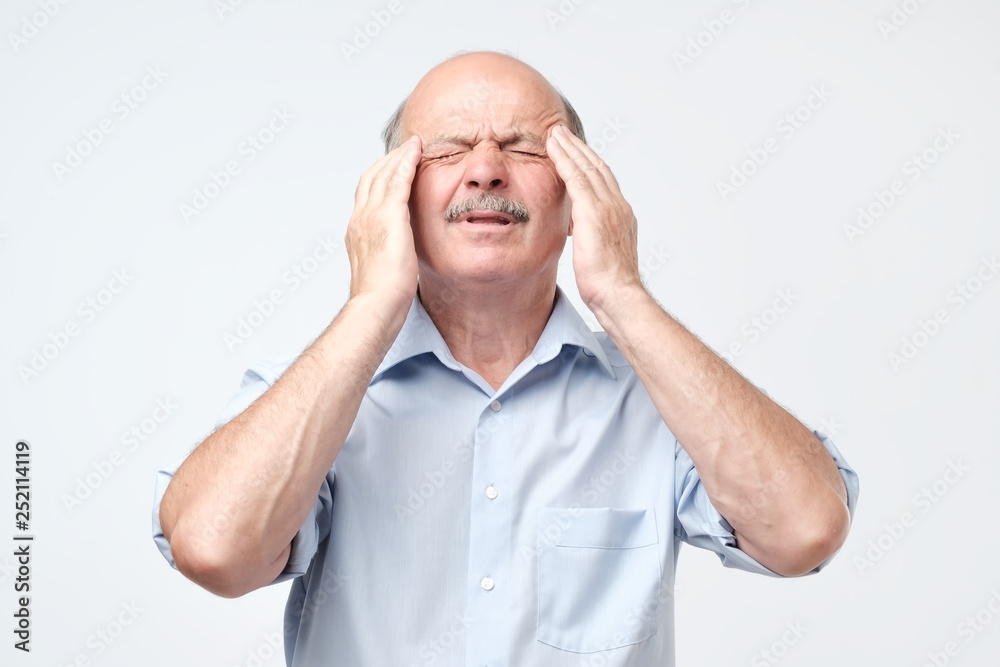 man holding head with both hands, suffering from headache man holding head with both hands, suffering from headache