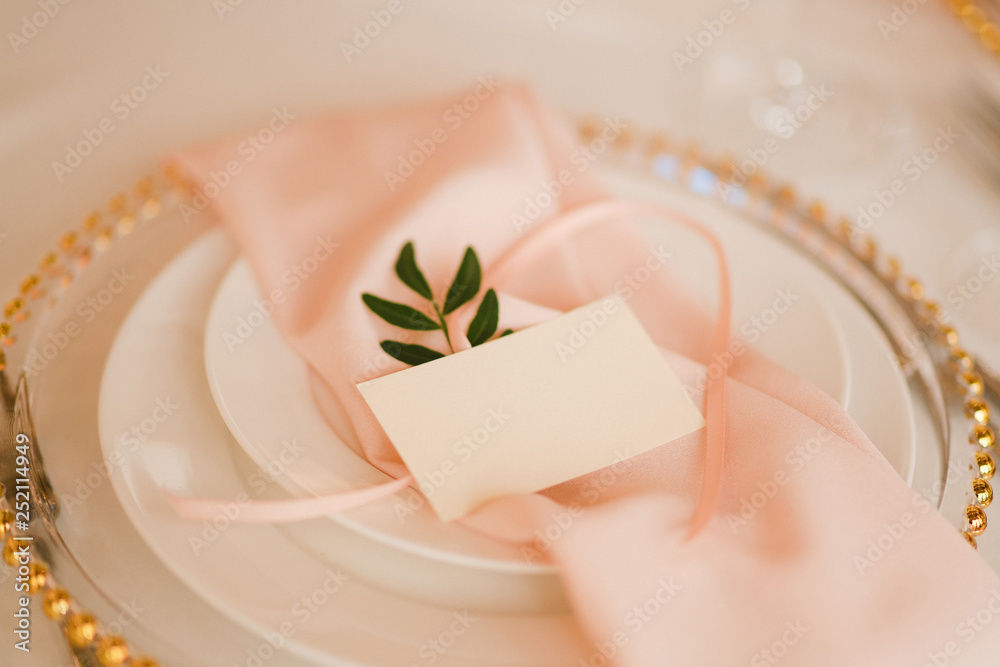 Coziness and style. Modern event design. Table setting at wedding reception. Floral compositions with name card on vintage plate on decorated table. Coziness and style. Modern event design. Table setting at wedding reception. Floral compositions with name card on vintage plate on decorated table.