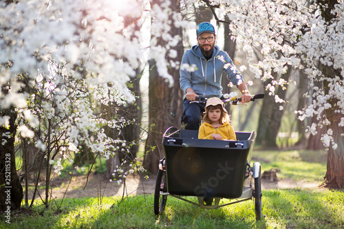 Father and daughter having a ride with cargo bike during spring photo