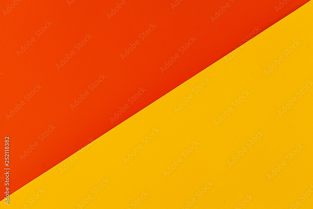 Vibrant orange and yellow colored plastic surfaces jointed diagonally, background.