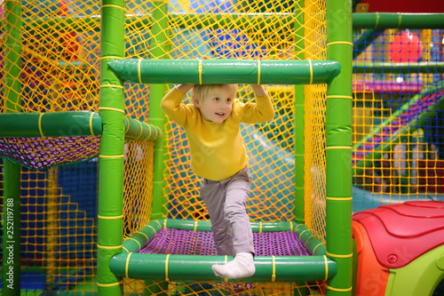 Happy little boy having fun in amusement in play center. Child playing on indoor playground. photo