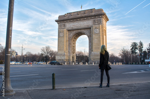 A blonde model with mermaid hair looking at the Arc of Triumph in Bucharest, Romania