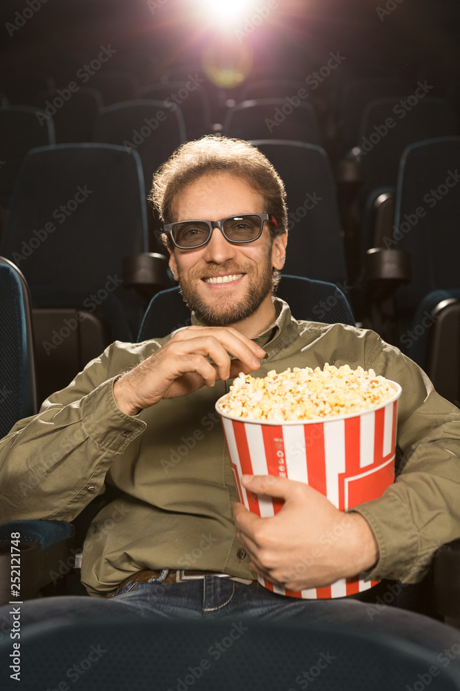 Handsome mature bearded man relaxing at the movie theatre alone