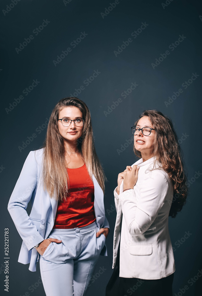 Two beautiful business women colleagues in office clothes in the studio. Women's fashion team corporation.