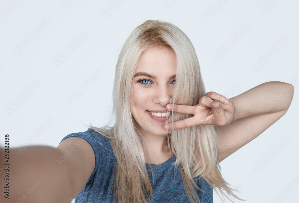 Young happy girl taking selfie with V-sign 