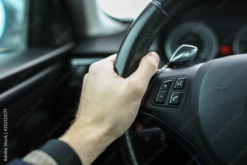 finger presses the button on the steering wheel of the car, speakerphone and cruise control.