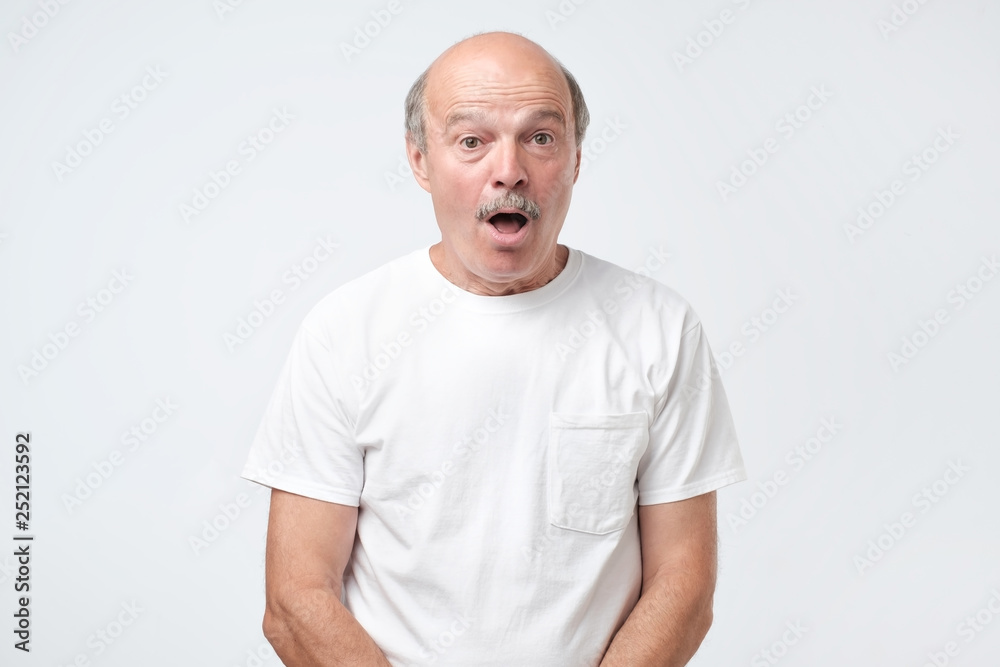 Wow concept. Senior emotional surprised man standing with opened a little mouth. Wow concept. Senior emotional surprised man standing with opened a little mouth.