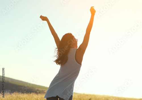 Happy girl with arms raised in sunshine 