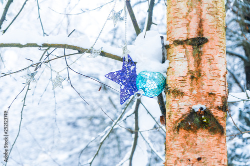 Christmas ornaments hanging on a tree in a snowy forest after a snow storm  depicting  winter time  cold weather  Christmas  holidays and winter wonderland.