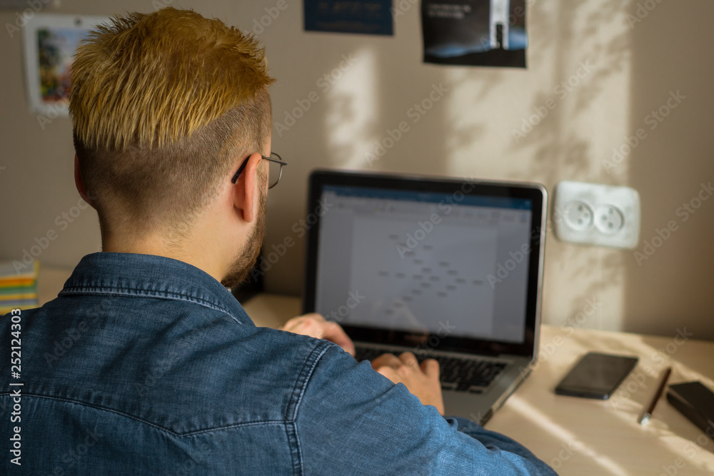 Young freelance guy works at home on a laptop Young freelance guy works at home on a laptop