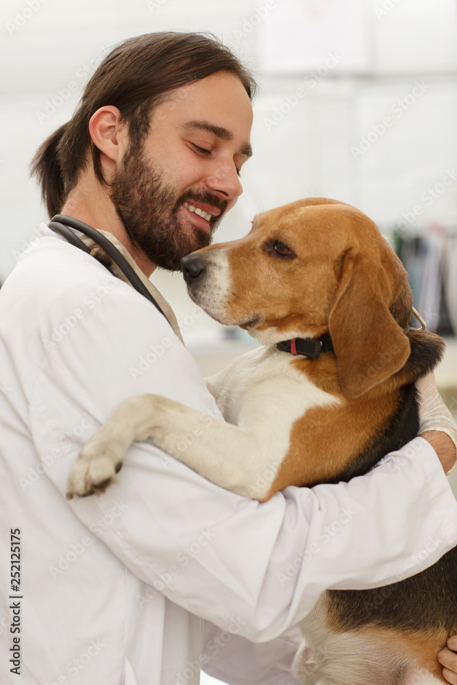 Adult man holding adorable dog and smiling.