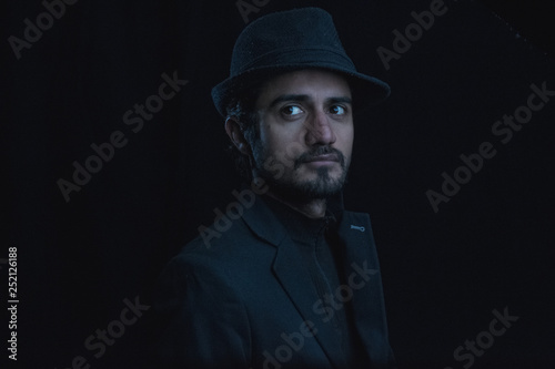 dark portrait of a young man with hat