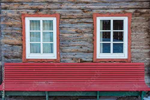 Holzwand, Fenster und rote Bank