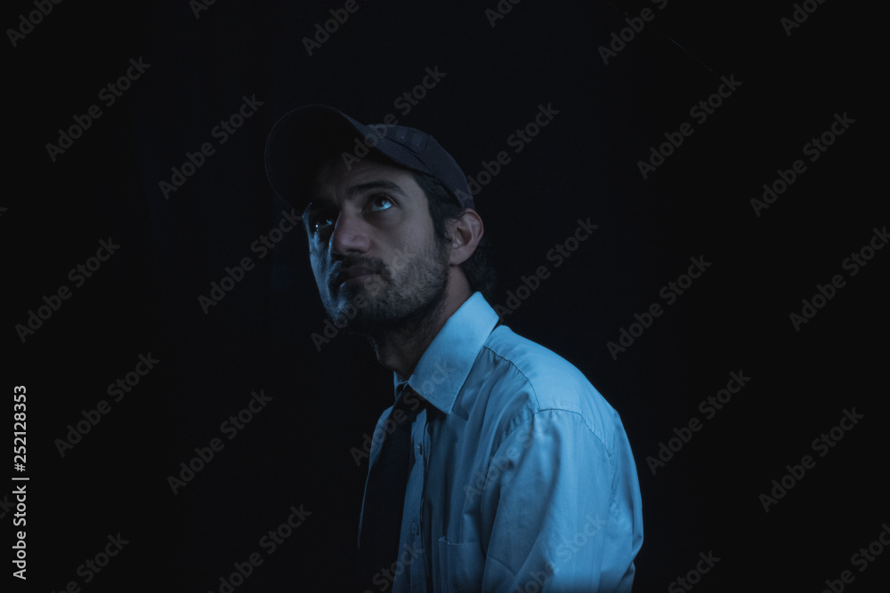 portrait with black background of a young man in cap shirt and tie portrait with black background of a young man in cap shirt and tie