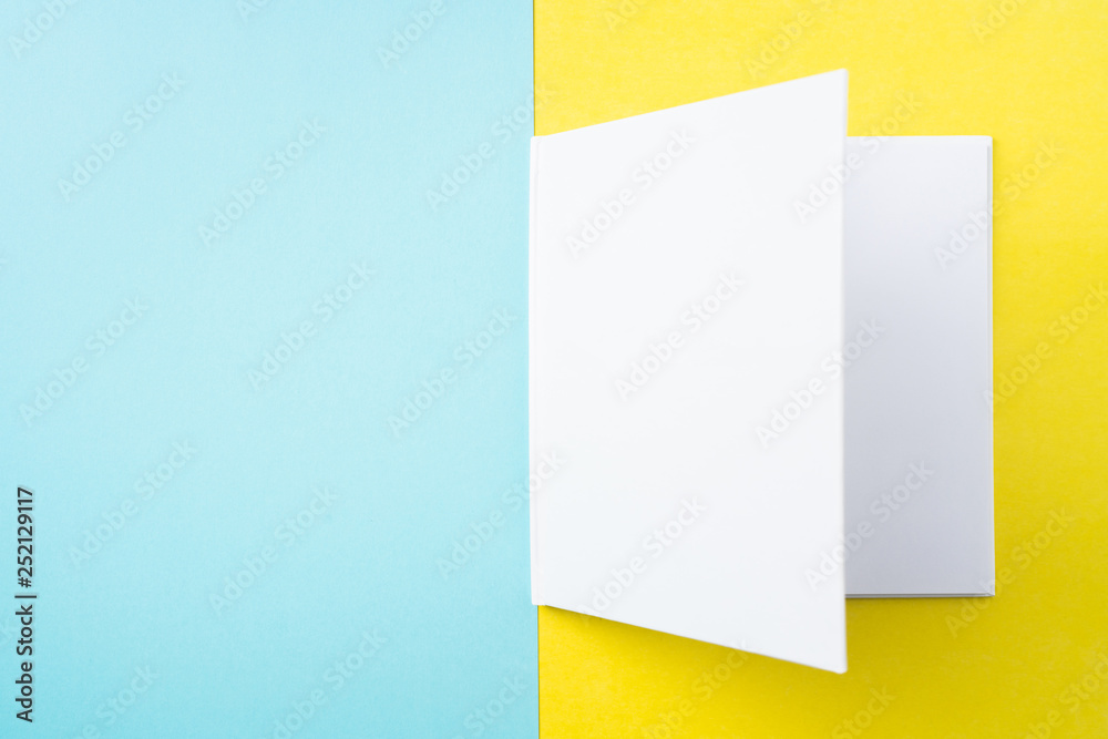 opened white square notebook on yellow and blue opened white square notebook on yellow and blue