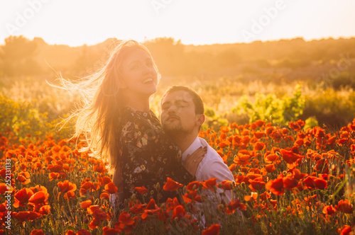 Man and woman embracing in poppy field on the dusk