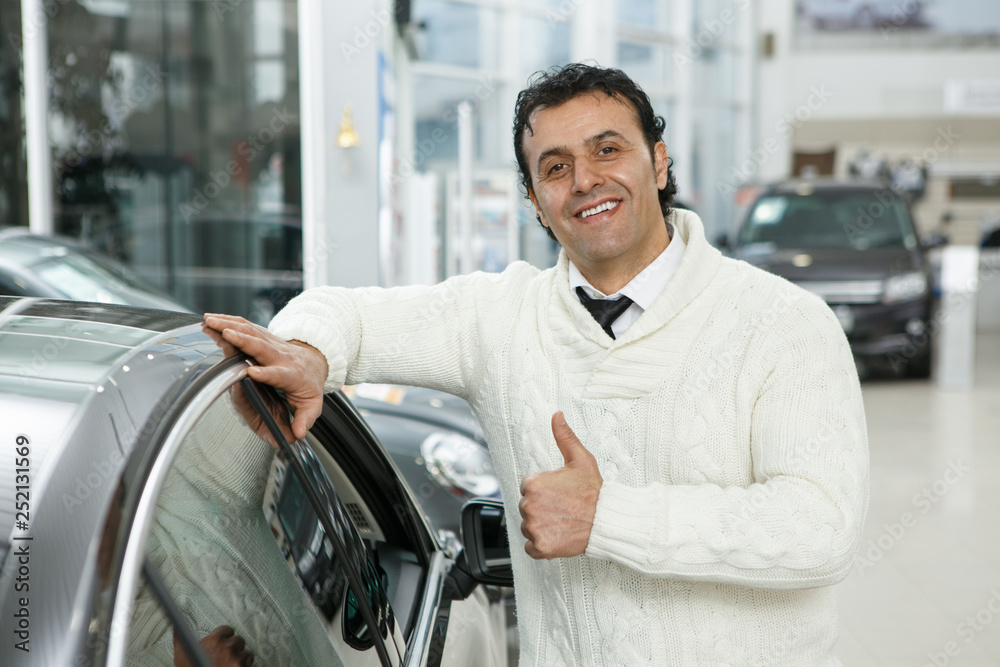Mature man choosing a new car at the dealership salon