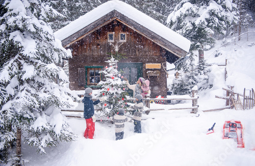Austria, Altenmarkt-Zauchensee, family decorating Christmas tree at wooden house photo