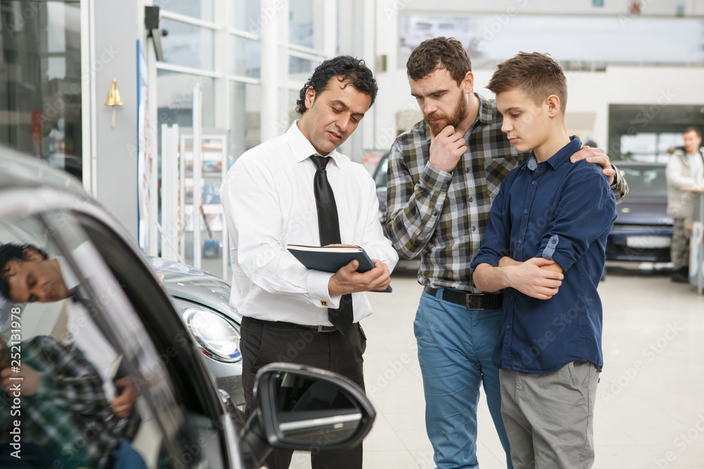 © Zoriana - Handsome mature man and his son buying a new car