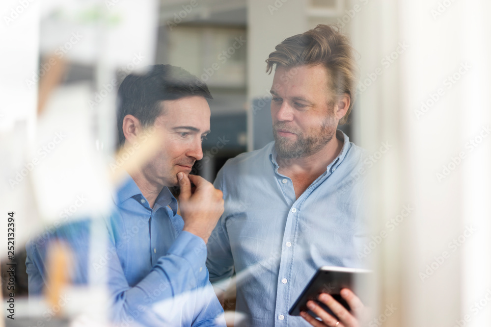 Two businessmen sharing tablet and thinking Two businessmen sharing tablet and thinking