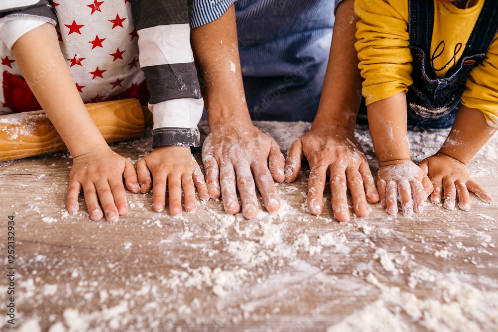 Mother and children with flour on their hands, partial view