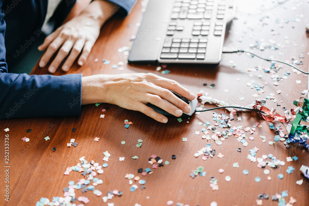 Hand of a woman working on a desk full of confetti Hand of a woman working on a desk full of confetti